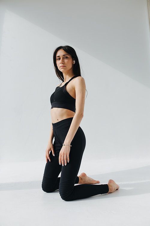 sportive armenian woman listening music in earphone while practicing yoga at home