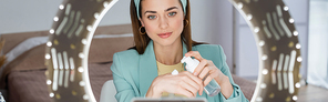 stylish woman applying face foam on hand near phone holder with ring lamp, banner