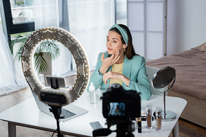 pretty beauty blogger applying face foam near devices and ring lamp