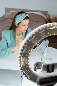 stylish beauty blogger near mirror, laptop and phone holder with circle light
