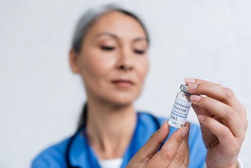 blurred asian physician holding vial with coronavirus vaccine