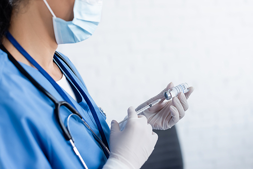 cropped view of doctor in medical mask filling syringe with vaccine