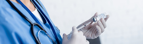 partial view of doctor in latex gloves filling syringe with vaccine, banner