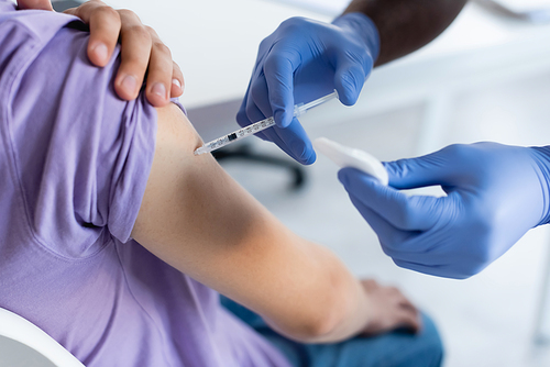 cropped view of african american man in latex gloves vaccinating young patient