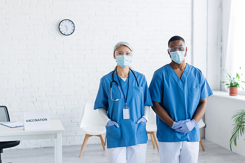 interracial doctors in medicals masks and goggles  in vaccination center