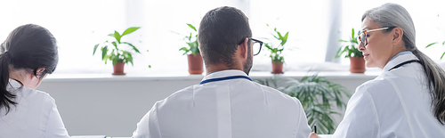 back view of young doctors near middle aged asian colleague in meeting room, banner