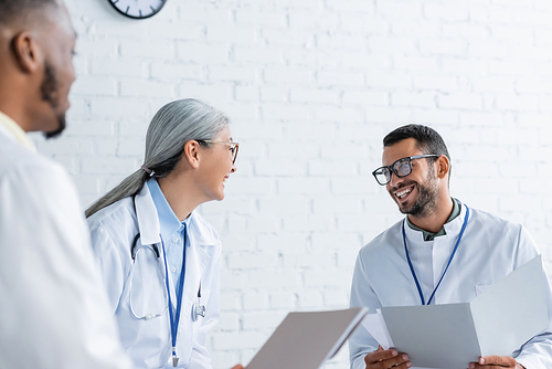 blurred african american physician near cheerful multiethnic colleagues talking during conference