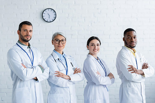 happy multicultural doctors in white coats standing with crossed arms and 