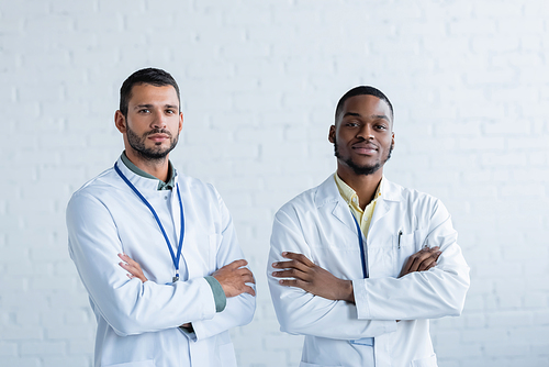 young interracial doctors in white coats standing with crossed arms and 