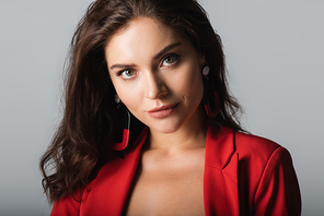 young woman in red suit and earrings  isolated on grey