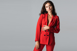 stylish young woman in red suit posing and  isolated on grey