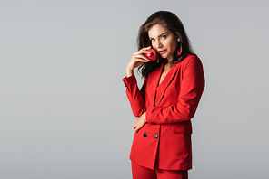 young woman in red suit posing with fresh apple isolated on grey