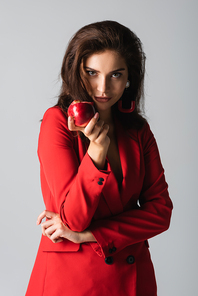 stylish woman in trendy suit holding red apple isolated on grey