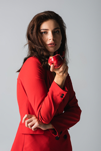 young woman in trendy suit holding red apple isolated on grey