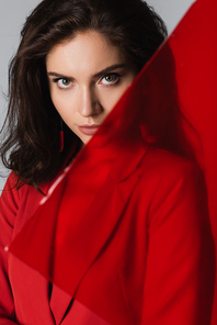 young brunette woman  near blurred red glass isolated on grey