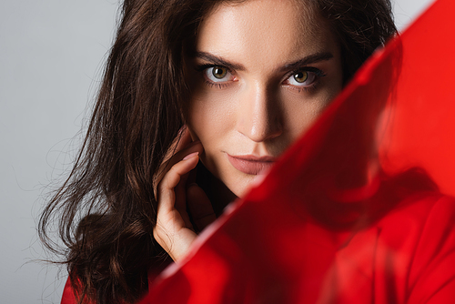 young woman  near blurred red glass isolated on grey