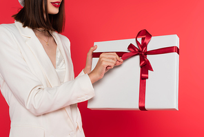 Cropped view of woman with red lips holding present isolated on red