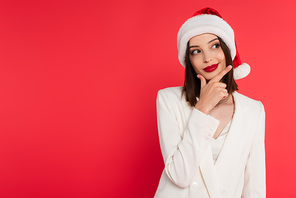 Pensive woman in santa hat and white jacket isolated on red