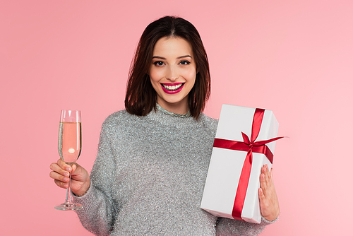 Pretty woman with champagne and gift  isolated on pink