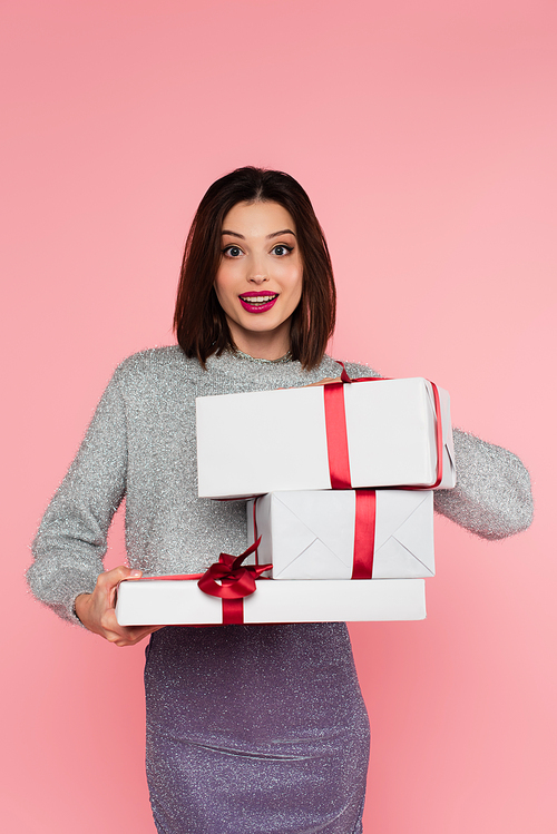 Happy stylish woman holding presents and  isolated on pink