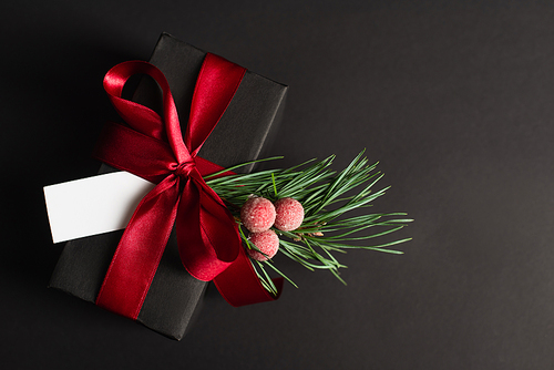 top view of wrapped gift box with red ribbon and blank card isolated on black