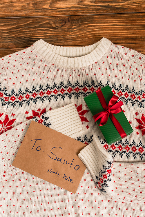 top view of letter to santa near gift box on knitted sweater