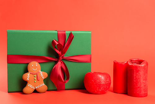 gingerbread cookie near green wrapped present and candles on red
