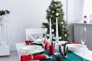 table served for festive dinner near christmas tree on blurred background