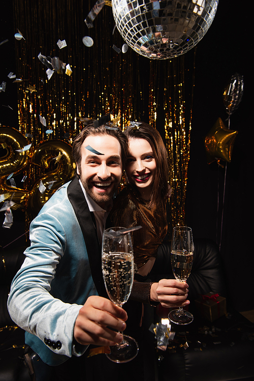 pleased couple  while celebrating christmas with champagne on black