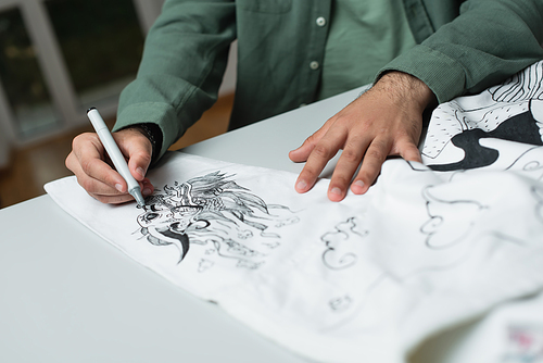partial view of fashion designer drawing on kimono with felt pen on blurred foreground