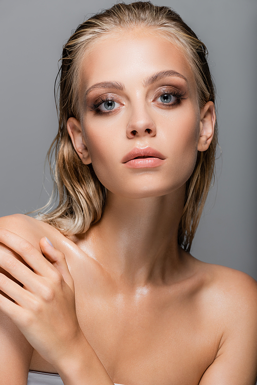 wet woman with perfect skin  while touching bare shoulder isolated on grey