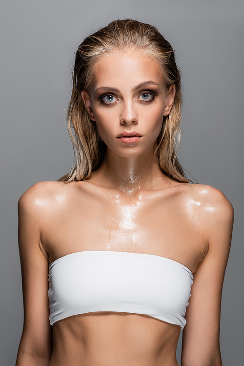 wet woman in white top with bare shoulders posing isolated on grey