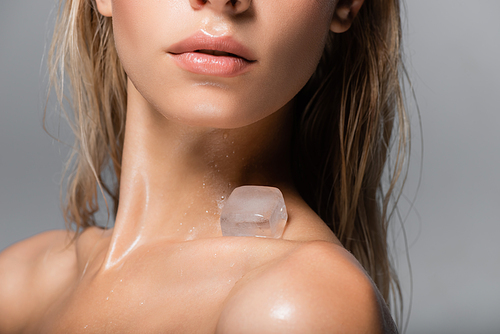 cropped view of young woman with ice cube on bare shoulder isolated on grey