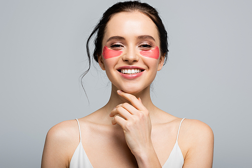 Happy young woman in eye patches  isolated on grey