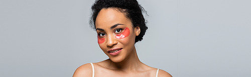 African american woman with eye patches smiling at camera isolated on grey, banner