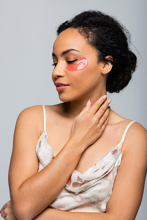 Pretty african american woman with eye patch touching neck isolated on grey