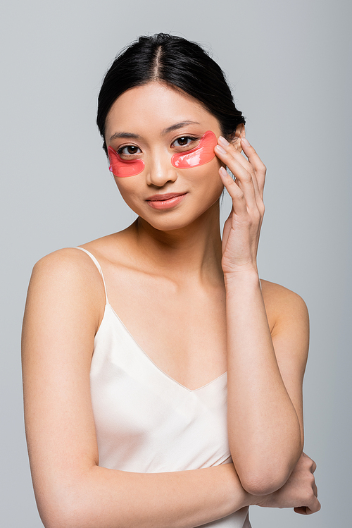 Young asian woman touching eye patch isolated on grey