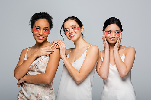 Smiling multiethnic women with eye patches  isolated on grey
