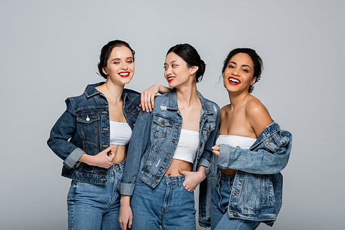 Pretty multiethnic women with red lips and denim jackets  isolated on grey