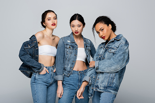 Pretty interracial women in denim jackets  isolated on grey