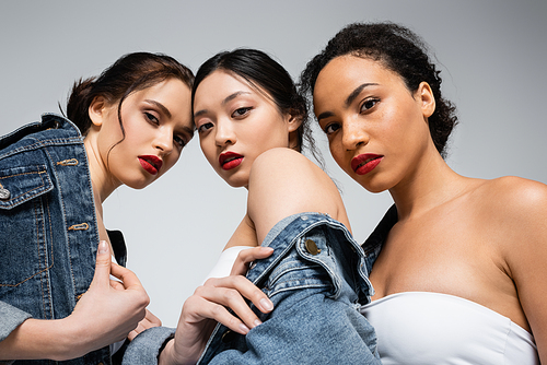 Low angle view of interracial women with red lips  isolated on grey