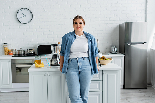 Smiling woman with overweight standing near food in kitchen