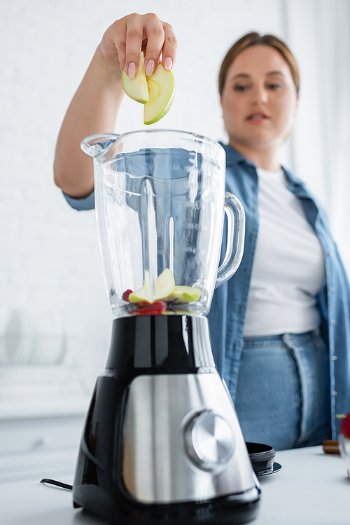 Blurred woman with overweight putting fruits in blender