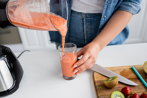 Cropped view of plus size woman pouring smoothie in kitchen