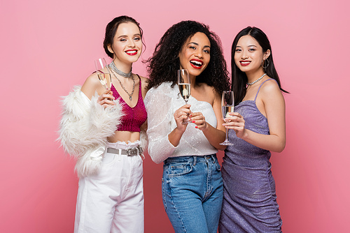 Happy and stylish multicultural friends with champagne  isolated on pink