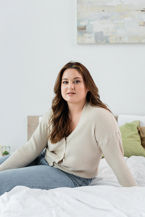 Pretty plus size woman  while sitting on bed in bedroom