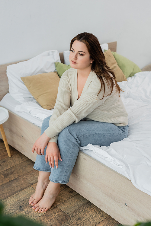 Brunette woman with overweight sitting on bed at home