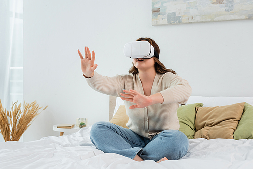 Plus size woman using virtual reality headset on bed