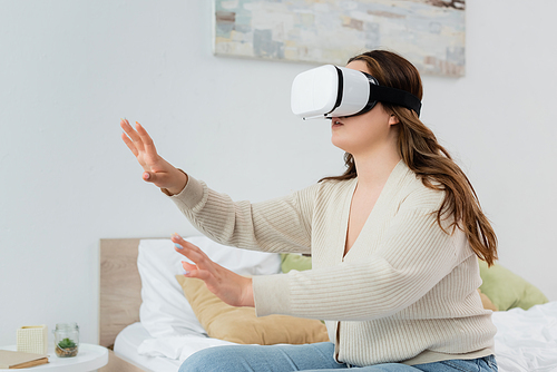 Brunette body positive woman in vr headset gaming in bedroom