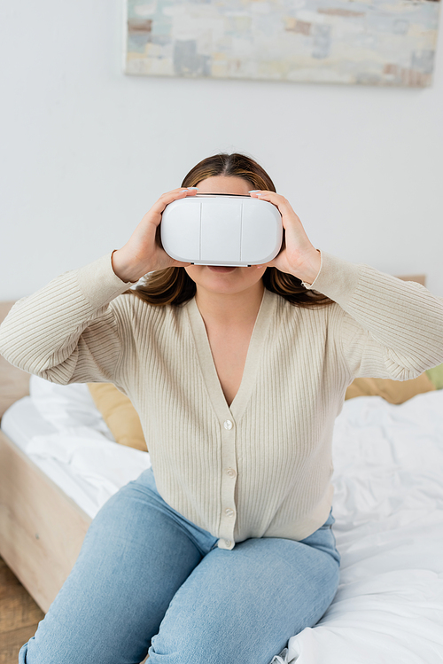 Young woman with overweight playing in virtual reality headset in bedroom